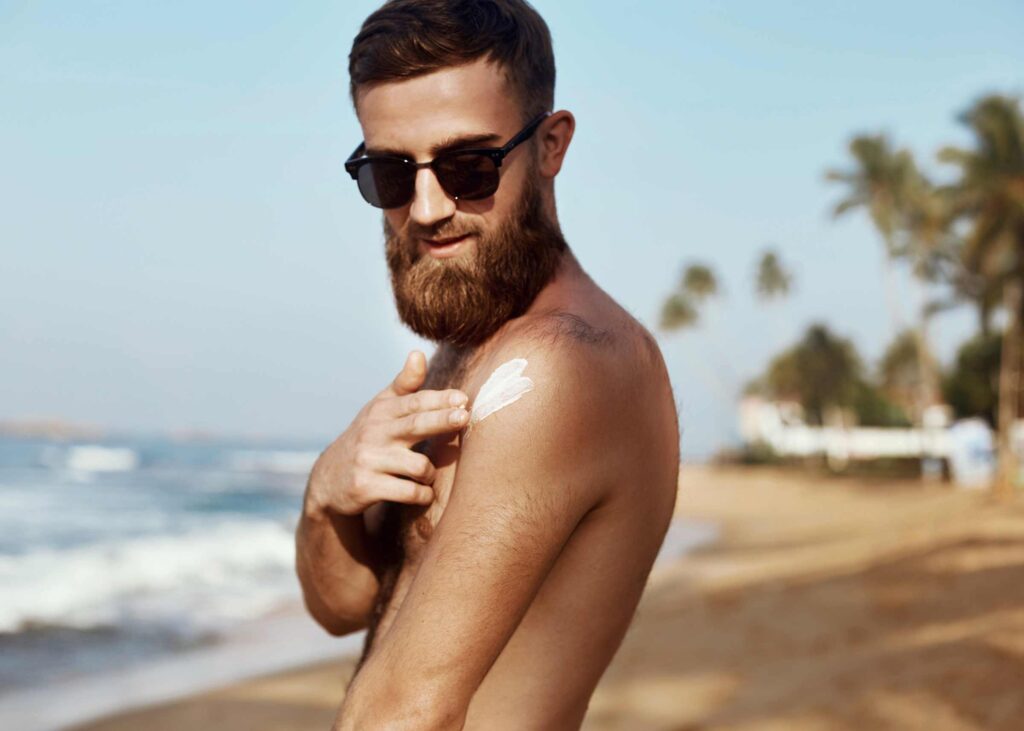 Man putting on vegan suntan lotion on the beach